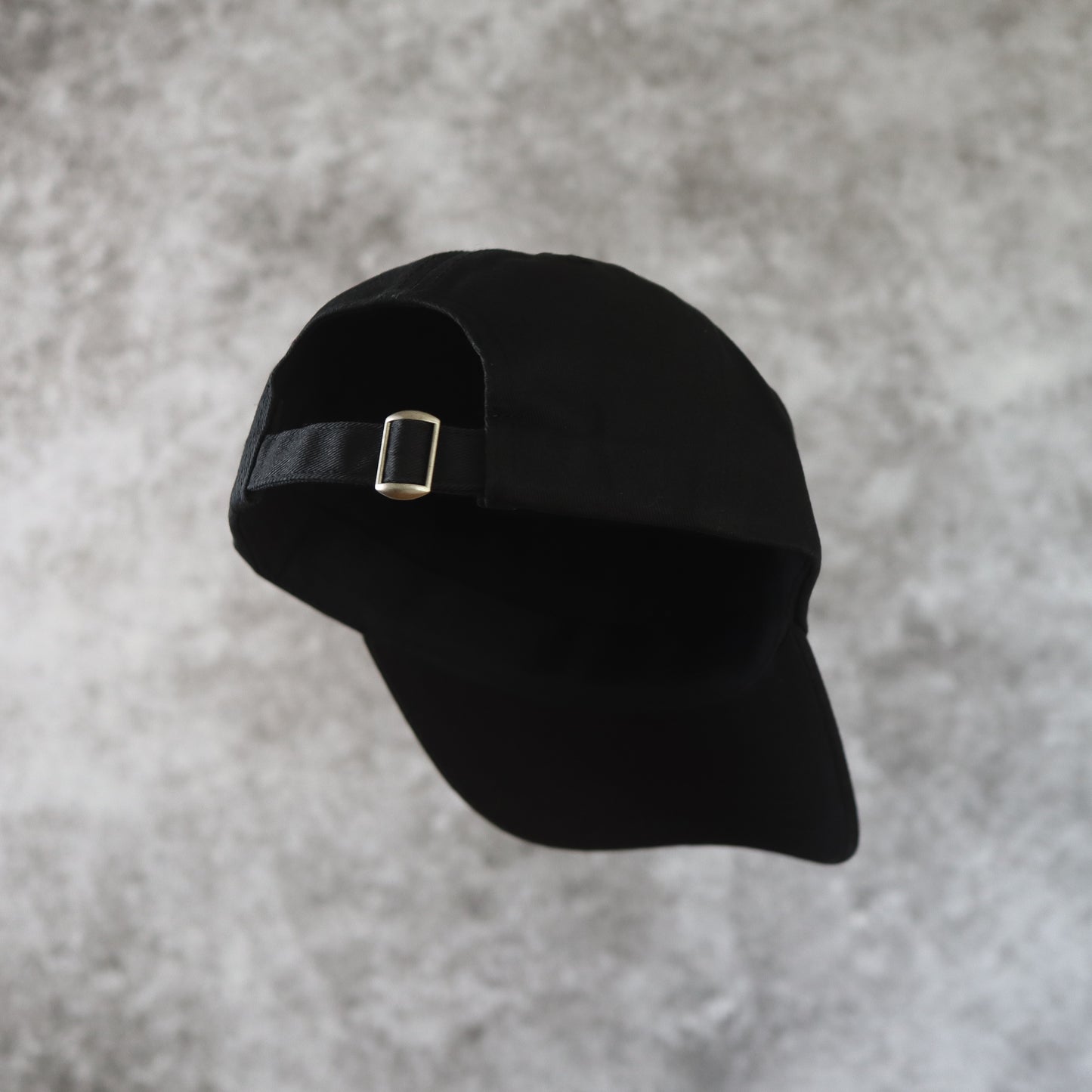 Baksida. Svart 6-panel keps med vit broderad logotyp. 100% organisk bomull. Justerbar rem. One size. Ostrukturerad front.