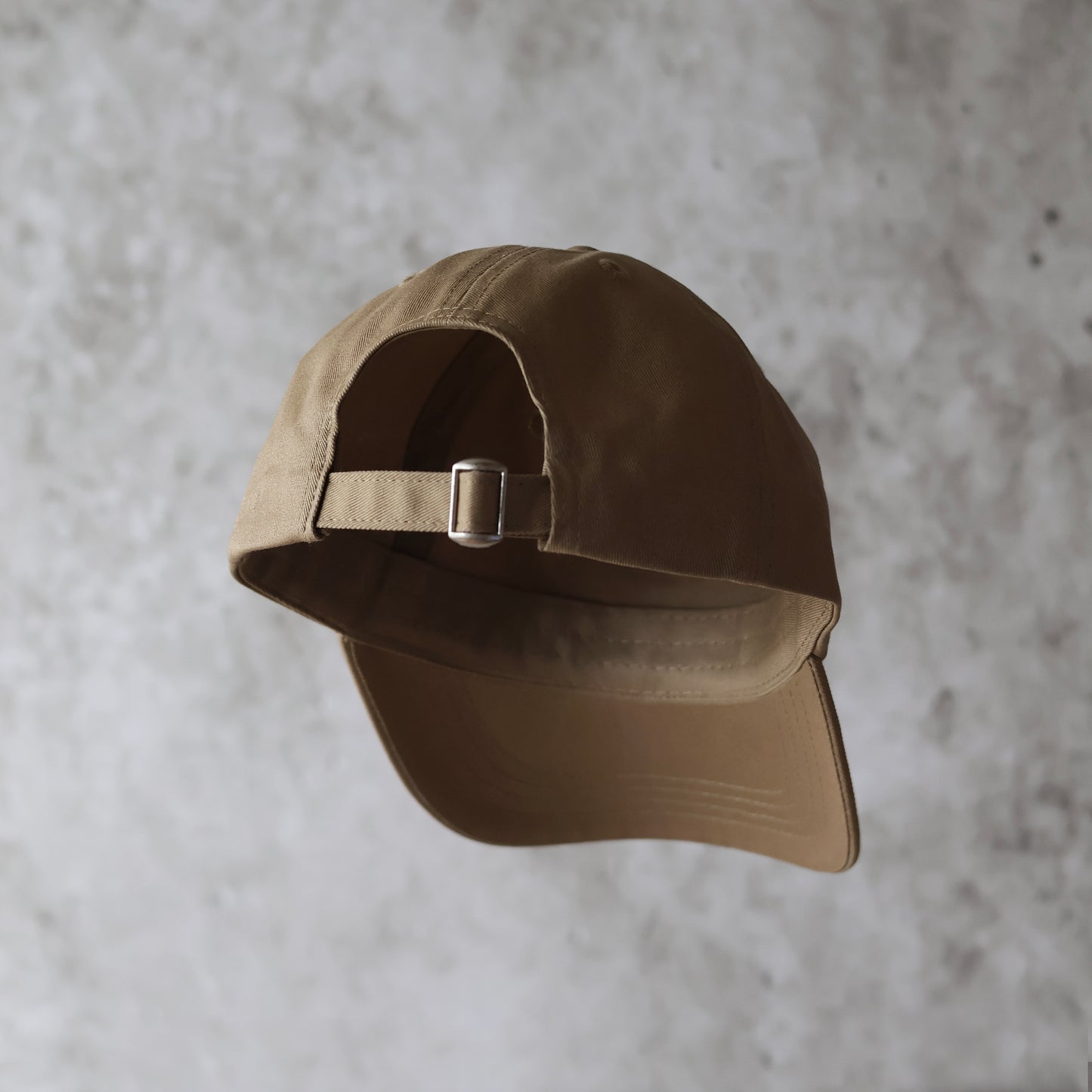 Baksida. Sand beige 6-panel keps med beige broderad logotyp. 100% organisk bomull. Justerbar rem. One size. Ostrukturerad front.