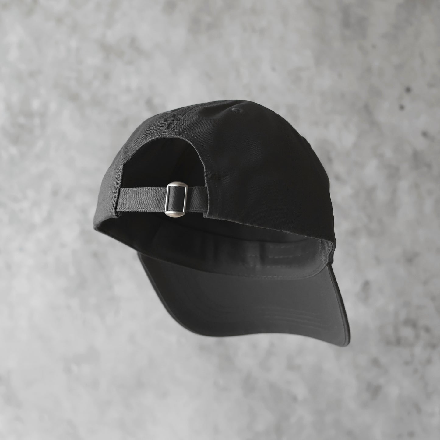 Baksida. Grå 6-panel keps med grå broderad logotyp. 100% organisk bomull. Justerbar rem. One size. Ostrukturerad front.